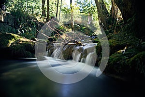 Long exposure of a river creek with a small waterfall. Sunset and strong detail bokeh view. blue calm warm water