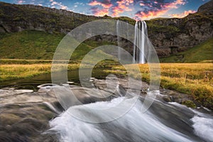 Long exposure of a river flowing from a waterfall on a cliff
