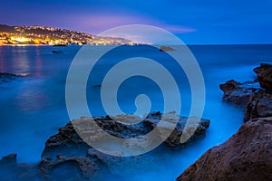 Long exposure of rocks and waves in the Pacific Ocean at twilight, at Monument Point, Heisler Park, Laguna Beach, California.