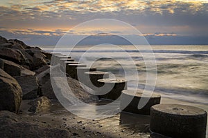 Long exposure of round wooden pilings on Folly Beach during sunset in Fort Fisher, North Carolina