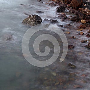 Long exposure of sea with smooth wave and rock