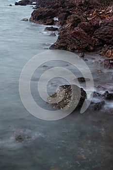 Long exposure of sea with smooth wave and rock