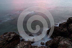 Long exposure of sea with smooth wave and rock