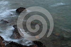 Long exposure of sea with smooth wave and rock