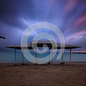 Long exposure sea wooden canopy on the beach at sunset