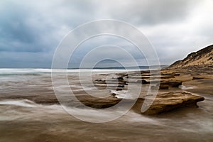 Long exposure seascape of ocean and rocks with dramatic cloudy sky, Anglesea, Victoria, Australia photo
