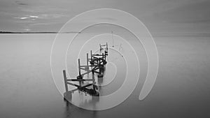 Long exposure shot of old broken jetty during pastel sunset.