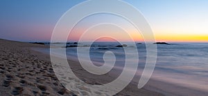 Long exposure shot over beach at dusk with milky ocean and smooth blue orange gradient sky