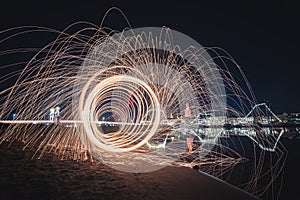 Long exposure shot of spinning steel wool creating sparks of light in a dark night sky