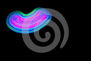 Long exposure, slow shutter, multicolor Led light painting of a spinning top on abstract dark black background.