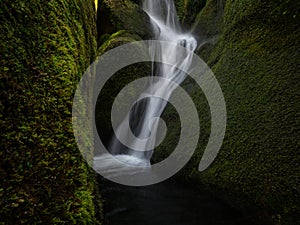 Long exposure of small freshwater river stream waterfall flowing through mossy rocks creek in Abel Tasman National Park