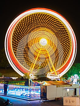 Long exposure of a spinning ferris wheel at night. Colorful funfair at night