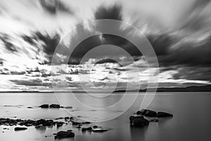 Long exposure view of a lake with perfectly still water and moving clouds