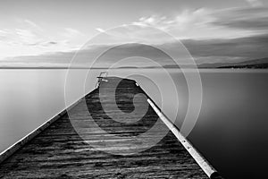 Long exposure view of a pier on a lake with perfectly still water