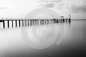 Long exposure view of a pier on a lake at sunset, with beautiful