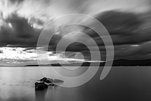 Long exposure view of a rock in Trasimeno lake Umbria, with moody sky
