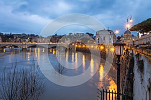 Long exposure view of Rome on a cloudy sunset, Tiber river and bridge with light set. Top view.