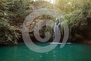 Long exposure waterfall during the day. green forest and rocky mountain. summer time. crystal clear blue water