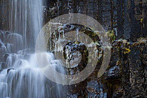 Long exposure of waterfall over basaltic rocks with ice