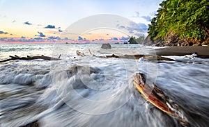 Waves crashing on driftwood at sunset, Costa Rica