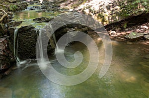 Long exposure of a woodland waterfall and reflecting pool.