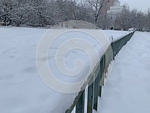 Long fence in the snow in a winter park.