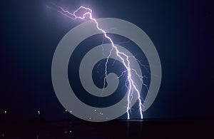 Long forked lightning bolt strikes down from a summer thunderstorm in Lake IJsselmeer, Netherlands