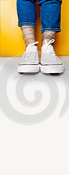 Long format banner, women legs in white clean new sneakers, transparent thin socks with silver shiny stars and blue jeans on