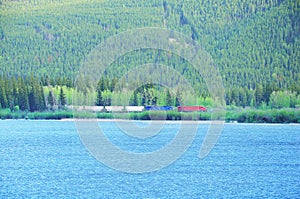 Long freight train moves by the lake in Canadian Rockies