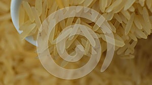 Long grain parboiled basmati rice pouring with spoon macro slow motion