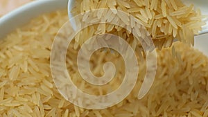 Long grain parboiled basmati rice pouring with spoon macro slow motion