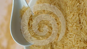 Long grain parboiled basmati rice pouring with spoon macro vertical slow motion