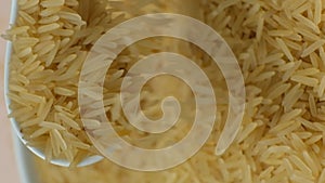 Long grain parboiled basmati rice pouring with spoon macro vertical slow motion