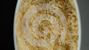 Long grain parboiled basmati rice rotating on black background vertical shooting