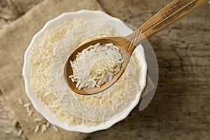Long grain rice in a wooden spoon on a background plate. Healthy eating, diet