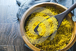 Long grain seasoned yellow rice on dark wooden spoon photo