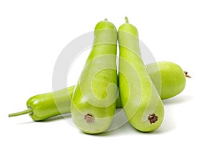 Long green bottle gourd stacked up together shown from one side. The fresh fruit has a light green smooth skin and a white flesh.