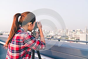 Long hair Asian woman taking cityscape photo on building rooftop in low light situation. Photography or hobby concept. With copy s