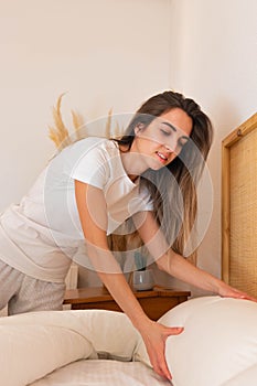 Long hair blonde woman chaning linen from bed as weekly routine in a boho decoration modern bedroom