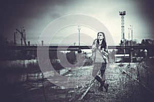 Long hair brunette girl outdoor with old industrial bridge behin