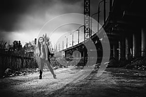 Long hair brunette girl outdoor with old industrial bridge behin