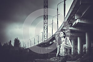 Long hair brunette girl outdoor with old industrial bridge behin