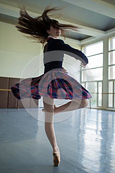 Long-haired ballerina spins in the dance moves on one leg to sta