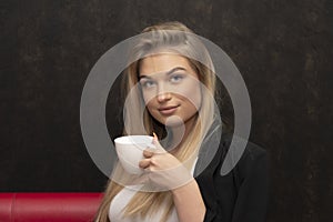 Long-haired blonde 20-25 years old with a white cup on a black background.