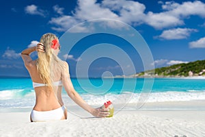 Long haired blonde woman with flower in hair in bikini on tropical beach