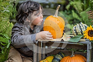 Long-haired brown-eyed boy in the garden making a pumpkin mask for Halloween, Austria