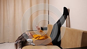 Long haired brunette in pullover on sofa types on smartphone