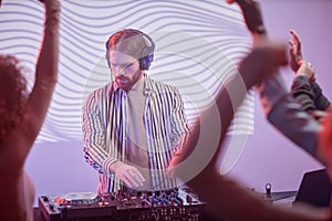 Long haired DJ by turntable in neon lights