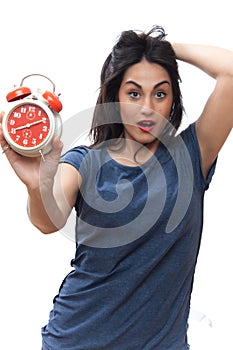 long-haired girl looks shocked at the alarm clock, business woman isolated on a gray background