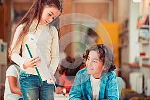 Long-haired girl showing an assignment to her classmate